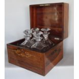 A French rosewood liqueur decanter box with floral marquetry detail containing four decanters and