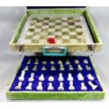 A green and white onyx chess board and matching pieces (complete) contained in a green velvet
