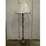 A brass floorstanding telescopic lamp standard with reeded tubular stem with foliate detail,