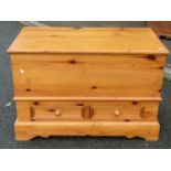A stripped pine blanket box with hinged lid over two small drawers set on a stepped plinth, 95 cm