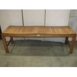 A pair of Peninsula collection low teak benches with shaped rectangular slatted seats raised on