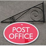 An oval wooden painted double sided exterior post office sign and wall mounted angular bracket