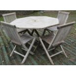 A weathered teak garden table, with octagonal slatted top raised on folding X framed supports,