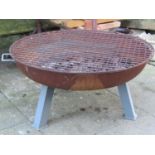 A contemporary, but well used, firepit with shallow circular two handled bowl, raised on three