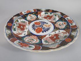 A 19th century imari type charger with male character and floral decoration, with shaped rim and