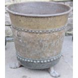 A large brass log bin of circular tapered form with pop riveted bands and raised on lions paw
