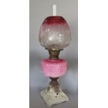 A Victorian oil lamp with pink font and rose tinted shade