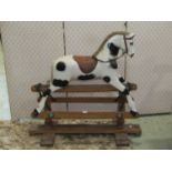 A small vintage child's rocking horse with painted finish, cast fittings and trestle base with two
