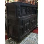 Antique oak court cupboard enclosed by two carved and panelled doors, the upper section recessed