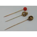 Three antique stick pins to include a yellow metal example with carved coral terminal and a