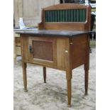 An Edwardian oak marble top washstand with raised green tiled splashback over a cupboard, panelled