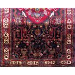Good quality Nahawand carpet with village type medallion and still life red decoration upon a dark