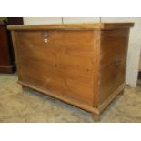 An antique stripped and waxed pine blanket box with hinged lid and drop steel carrying handles,