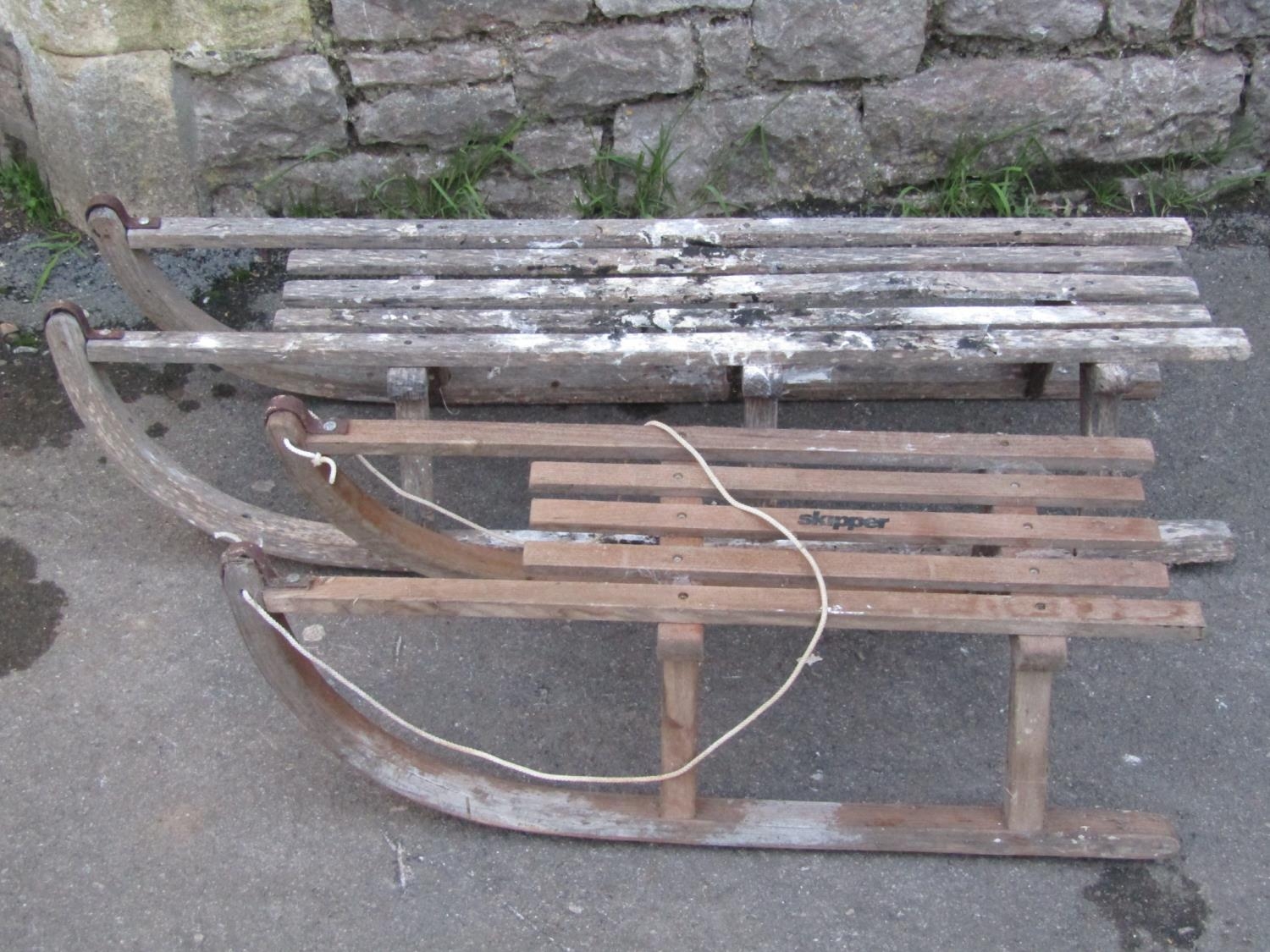 Two wooden toboggans of varying size with open slatted seats