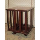 An Edwardian mahogany table top revolving bookcase of square cut form, with open slatted divides and