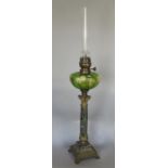 An oil lamp, floral green glass font, raised on a marble corinthian column decorative brass base, 80