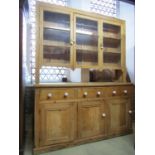 A reclaimed stripped and waxed pine farmhouse kitchen dresser in two sections, the lower enclosed by