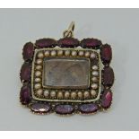 Antique yellow metal mourning brooch / pendant set with borders of flat cut garnets and seed