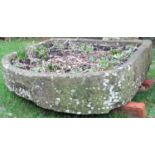 A large weathered shallow D shaped natural stone trough, 118cm wide x 108cm deep x 25cm high (af) (