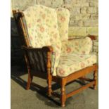 An Ercol colonial wing armchair with turned spindle and arcaded back within a moulded frame with