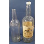 A large empty Haig gold label whisky bottle with labels, one gallon capacity and one further bottle