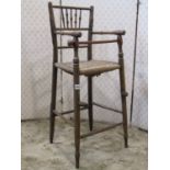 A countrymade Sussex style antique child's high chair with rush seat and turned framework, (af)