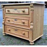 A stripped pine bedroom chest of three long drawers, flanked by carved and moulded detail and raised