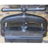 A cast iron book press with central screw thread and club shaped handle, approx 50 cm wide x 25 cm