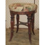 A Regency mahogany piano/music stool with circular upholstered seat raised on ring turned, tapered