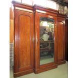 A Victorian mahogany breakfront sectional wardrobe enclosed by three full length moulded arched