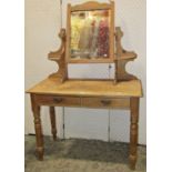 A late Victorian/Edwardian stripped pine dressing table, the raised central swing mirror with