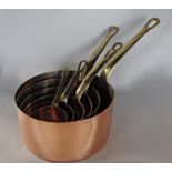 A graduated set of six copper and brass handled saucepans
