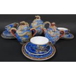 A collection of Japanese eggshell porcelain tea wares with moulded dragon detail on a blue ground