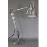 A modern angle poise brush steel desk lamp on a circular pad base