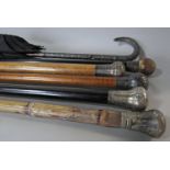 A collection of five walking sticks some with silver knobs and a silver handled umbrella (6)