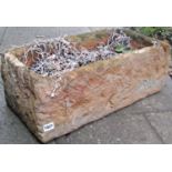 A rectangular garden planter in the form of a mock rough hewn stone trough (composite material),