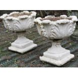 A pair of painted composition stone garden urns with circular acanthus leaf bowls raised on fluted
