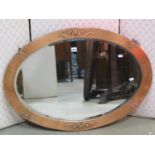 An arts and crafts style oval wall mirror with bevelled edge plate, within a copper clad and