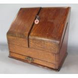 An early 20th century oak desk top stationery box opening to reveal a calendar and letter divisions,
