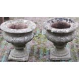 A pair of weathered cast composition stone garden urns of circular form with flared rims, lobed