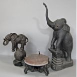 A bronzed finish baby elephant standing on a world globe, a wooden carved performing elephant and