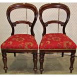 A set of three Victorian mahogany balloon back dining chairs with carved bar splats, upholstered