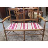 An Edwardian lightweight two seat sofa with stained beechwood frame, pierced vase shaped splats,