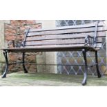 A two seat garden bench with stained hardwood lathes raised on cast iron end supports with