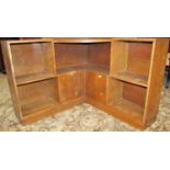 An early 20th century oak floorstanding low corner open shelving unit partially enclosed by two