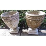 A pair of cast composition stone garden planters of circular tapered form with C scroll geometric