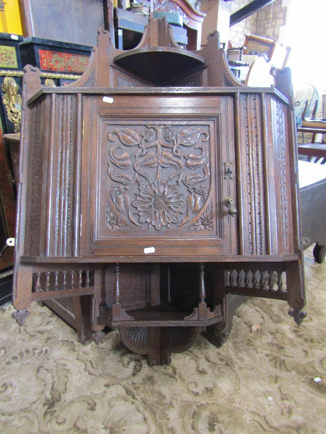 A late Victorian oak hanging corner cupboard, enclosed by a square panelled door with carved foliate