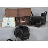 A leather photographers bag with flash guns, lenses and a cased Minolta camera