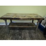 An industrial work bench, the heavy plank pine top raised on a cast iron and painted framework,