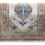 A modern design middle eastern rug with central stepped medallion upon a pale cream ground, 200cm
